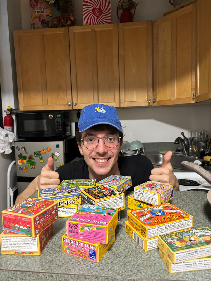 A customer in front of various Fishwife products giving thumbs up.
